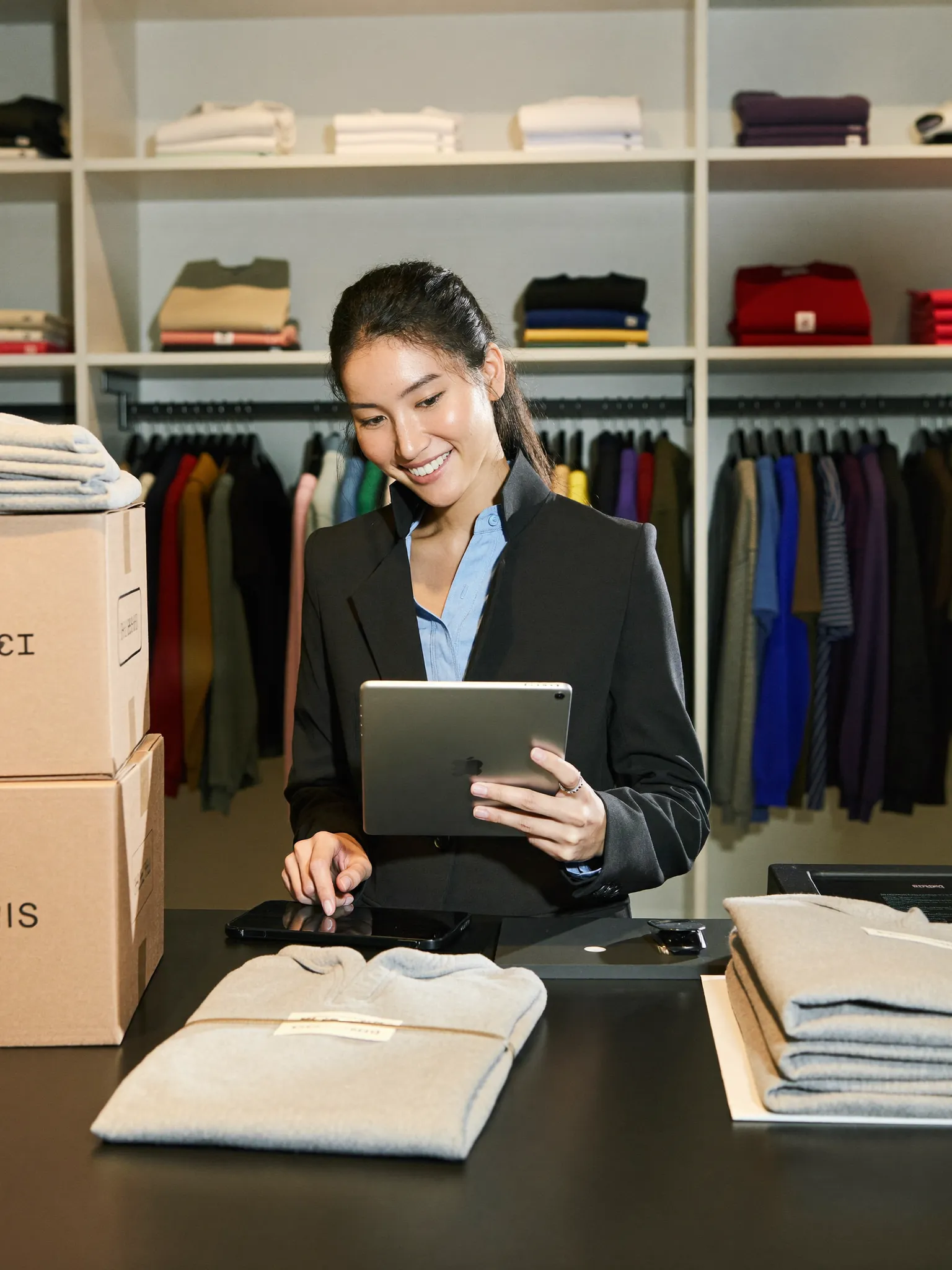 Professional attending to a tablet behind the counter of a clothing store